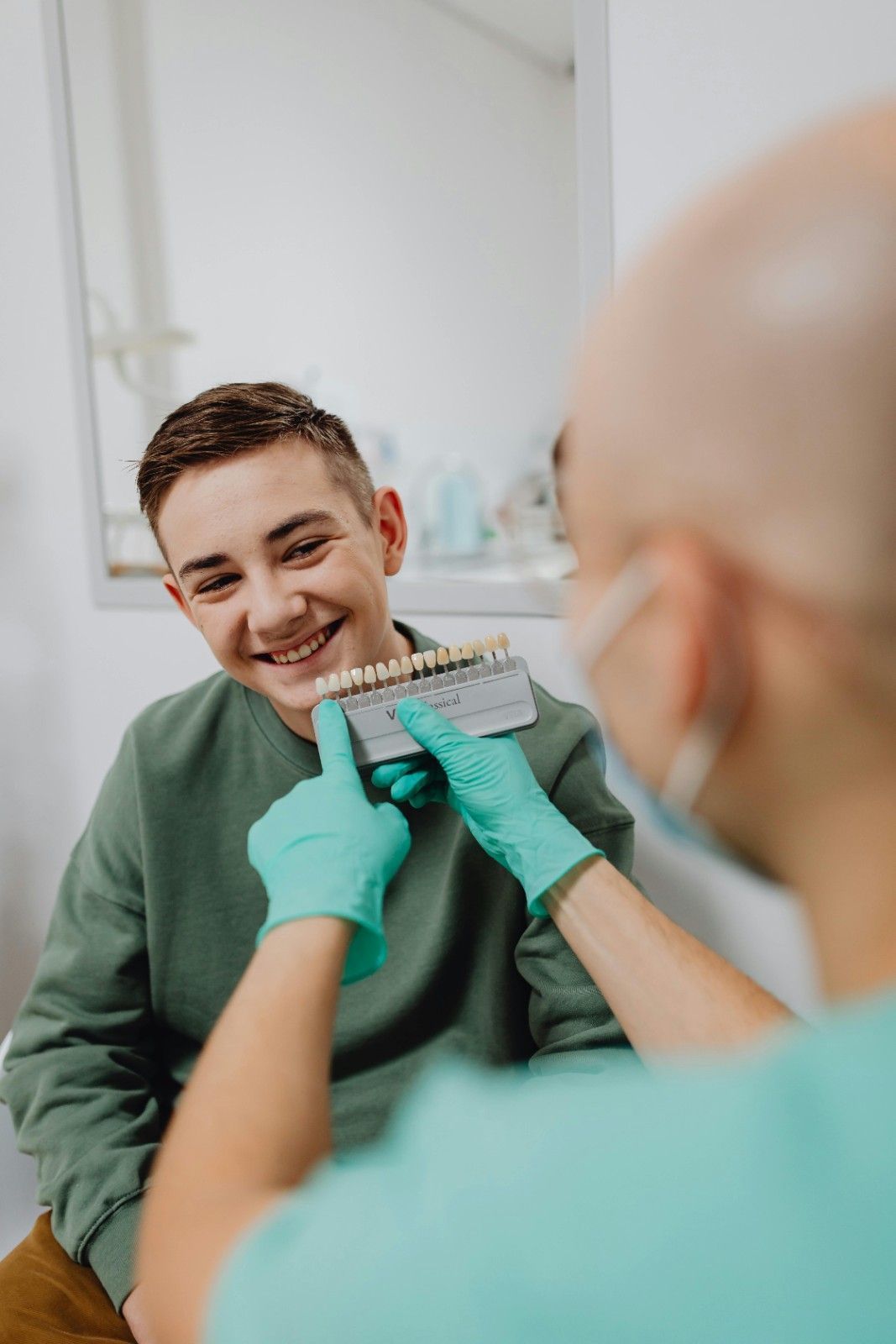 Dentista sosteniendo un molde dental de un paciente sonriente en una clínica.