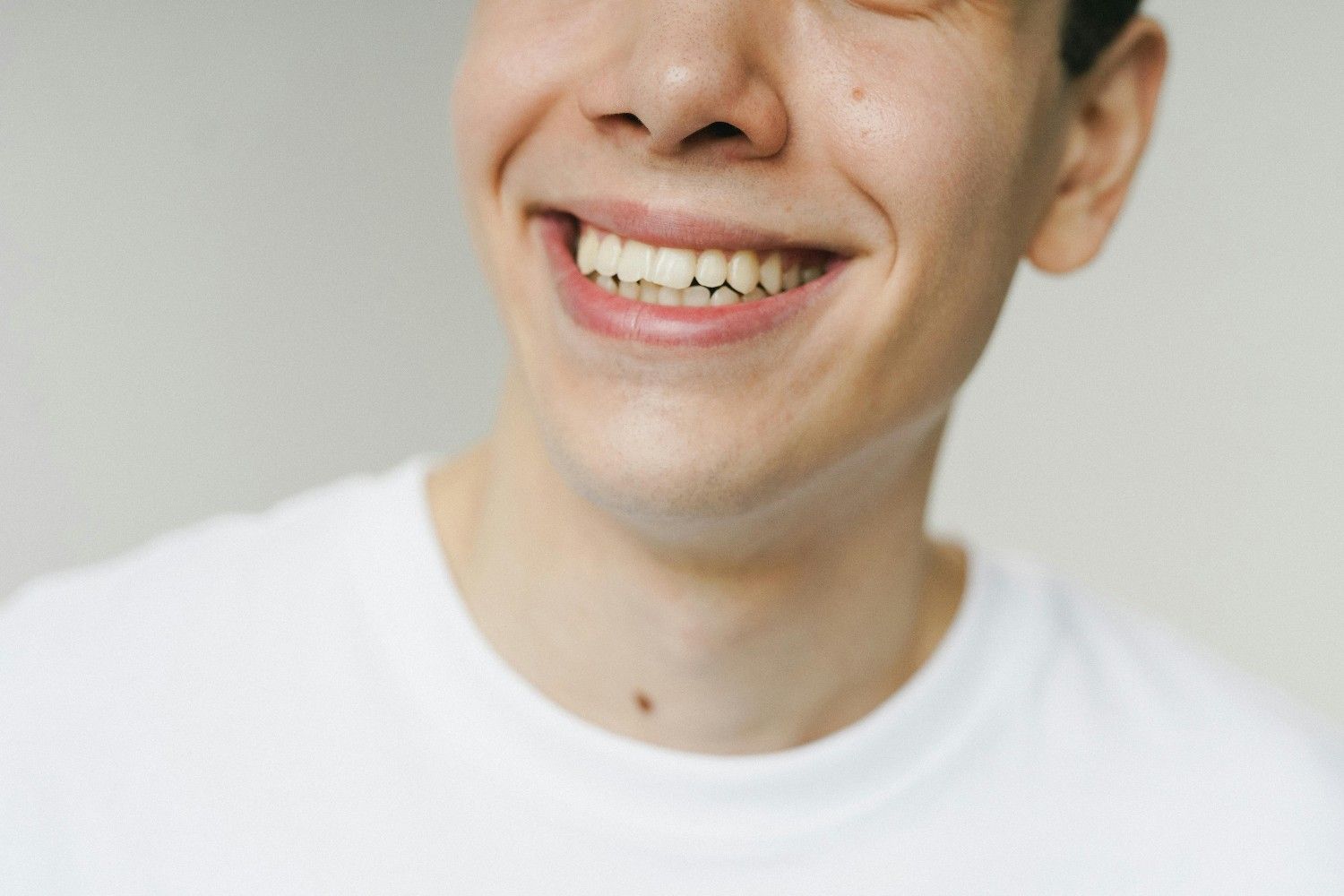 Persona sonriente con camisa blanca sobre fondo claro.