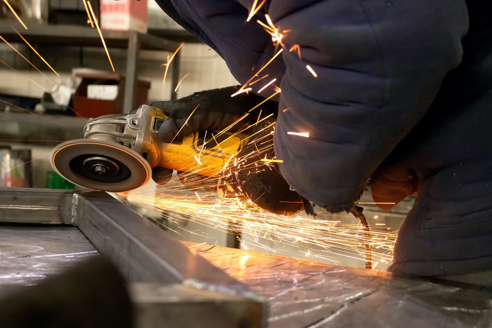Une personne utilise une meuleuse d'angle sur du métal dans un atelier.