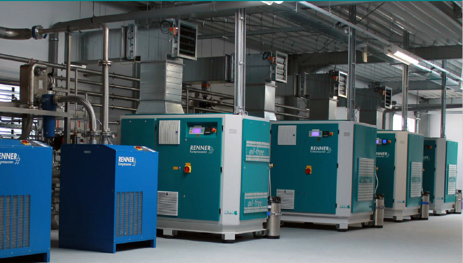 Rangée de compresseurs d'air industriels, bleus et turquoise, dans un environnement d'usine.