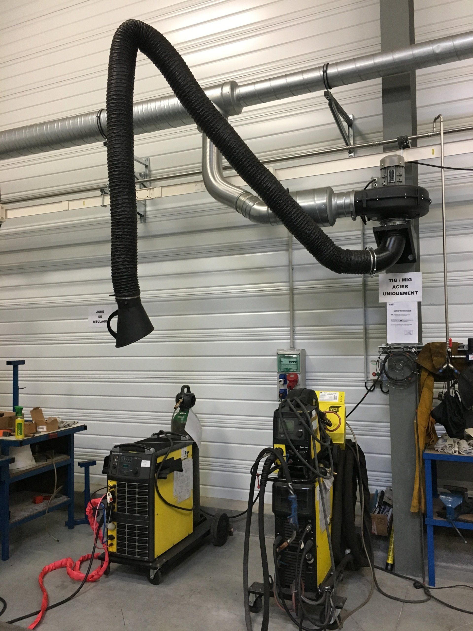 Une installation de soudage industriel avec un extracteur de fumées suspendu dans un atelier.