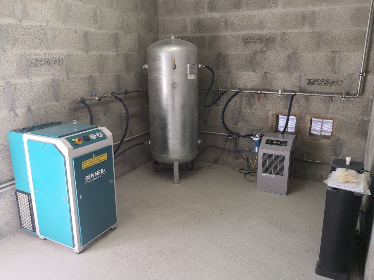 Un système de compresseur d'air industriel dans une pièce aux murs gris.