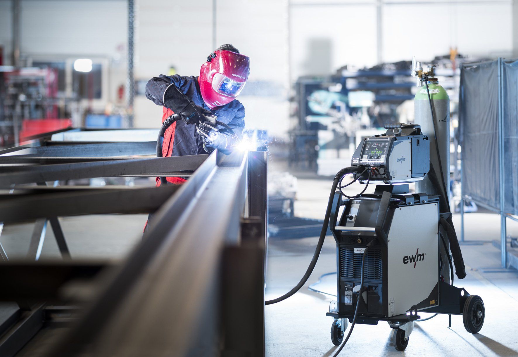 Soudeur en casque rouge soudant une structure métallique dans un atelier