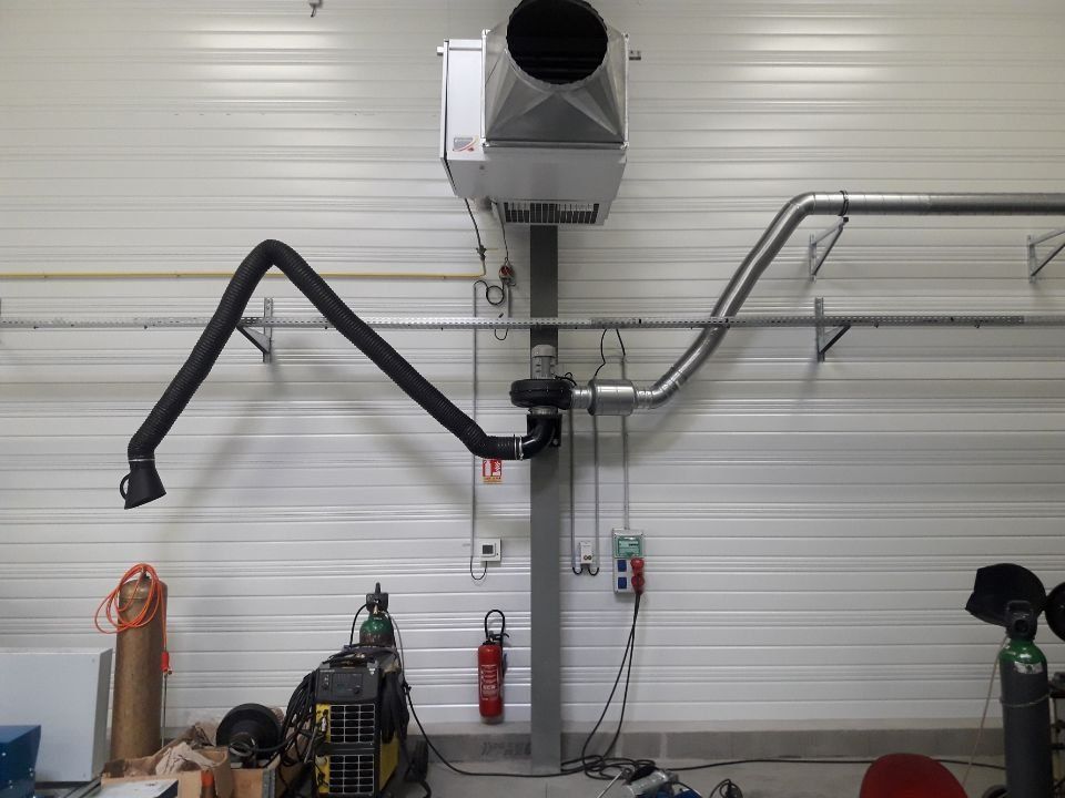 Système d'extraction des fumées de soudage monté sur un mur blanc avec un bras flexible et une unité suspendue.