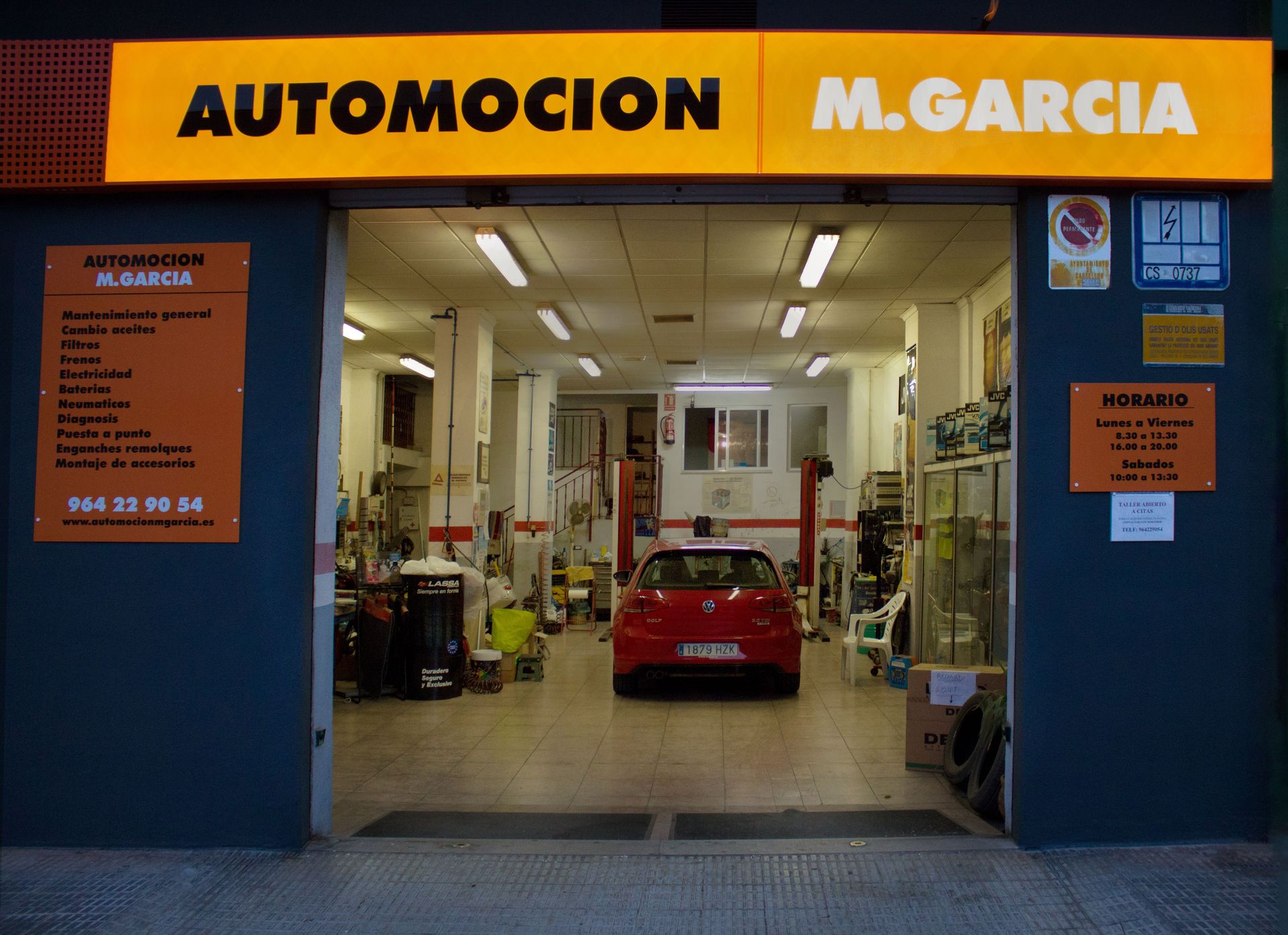 Entrada de garaje con coche dentro y cartel que dice