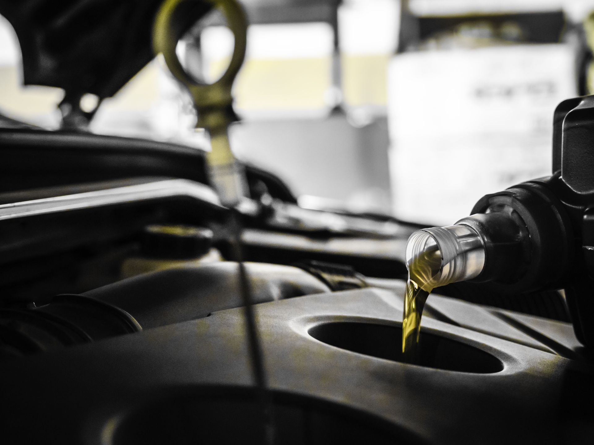 Se vierte aceite en el motor de un automóvil; el capó está abierto.