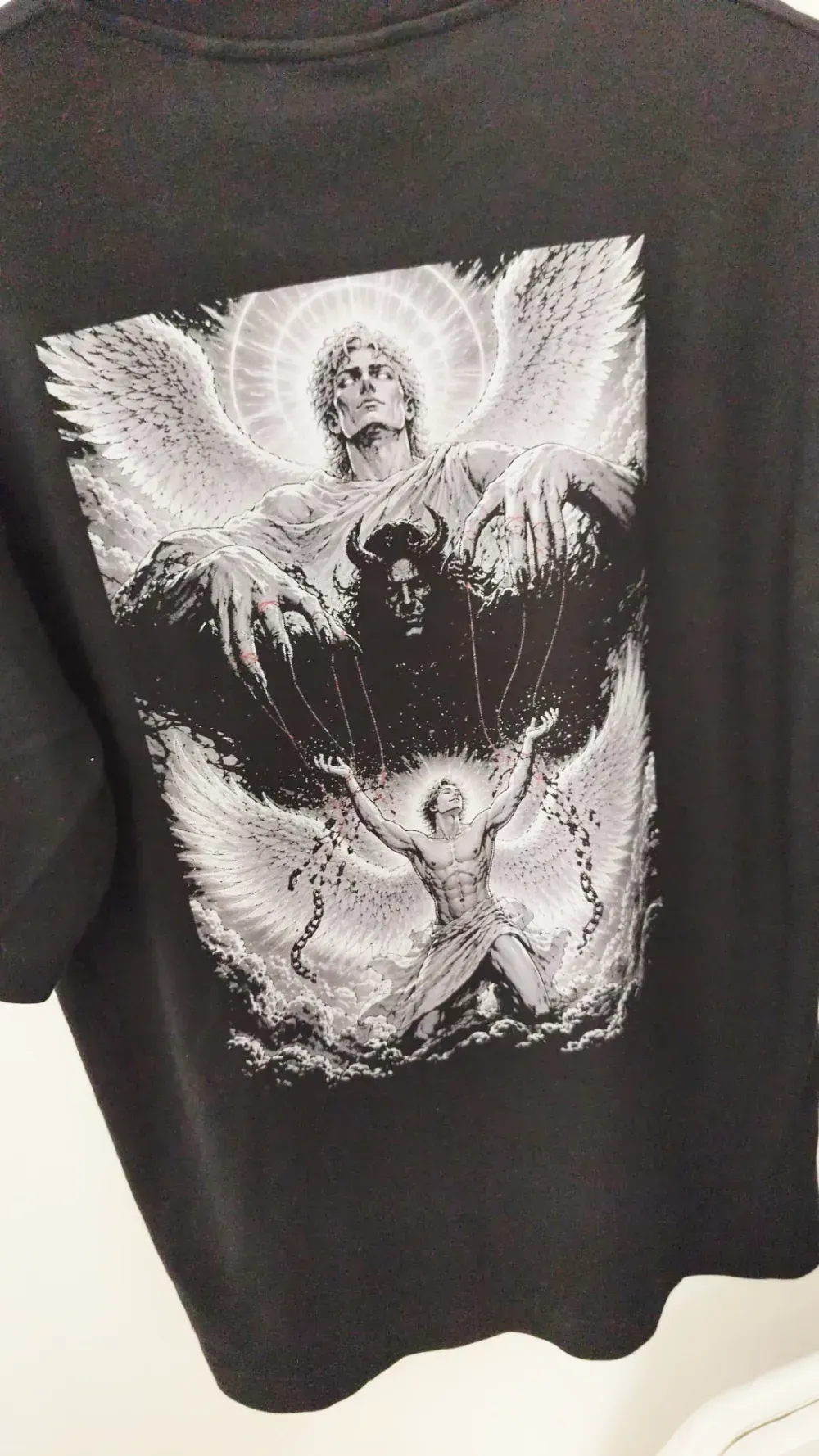 Sudadera negra con un gráfico de un ángel gótico blanco en la espalda, con alas y una figura central.