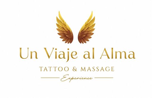 Logotipo de tatuaje y masaje dorado con la inscripci&oacute;n &ldquo;Un Viaje al Alma&rdquo; y alas sobre fondo blanco.