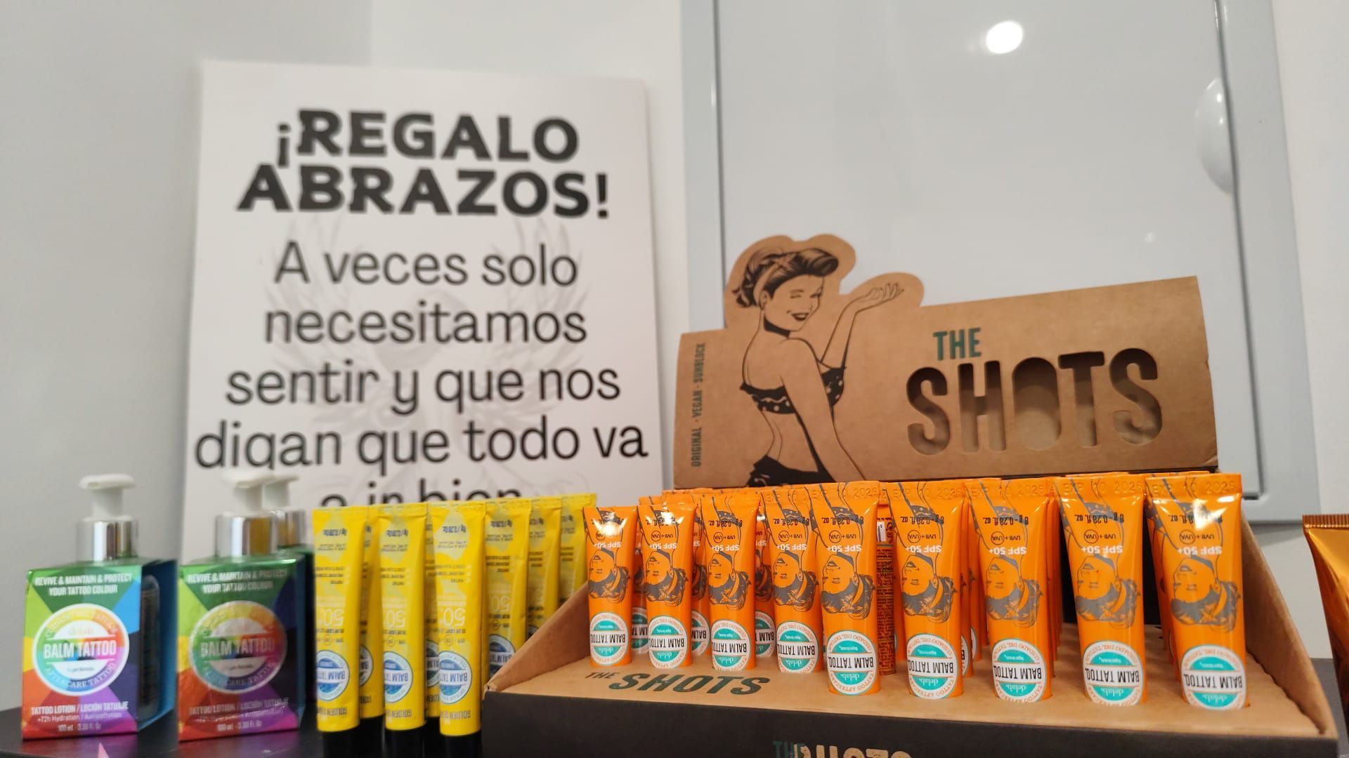 Exhibición de productos The Shits de color naranja y amarillo junto a un cartel promocional .
