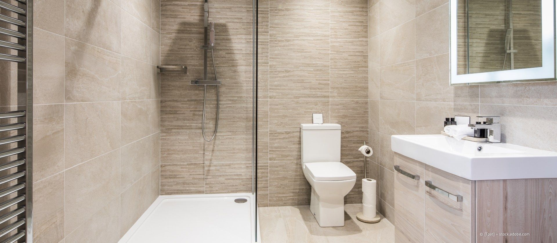 Modernes beigefarbenes Badezimmer mit Dusche, WC, Waschtisch und Spiegel