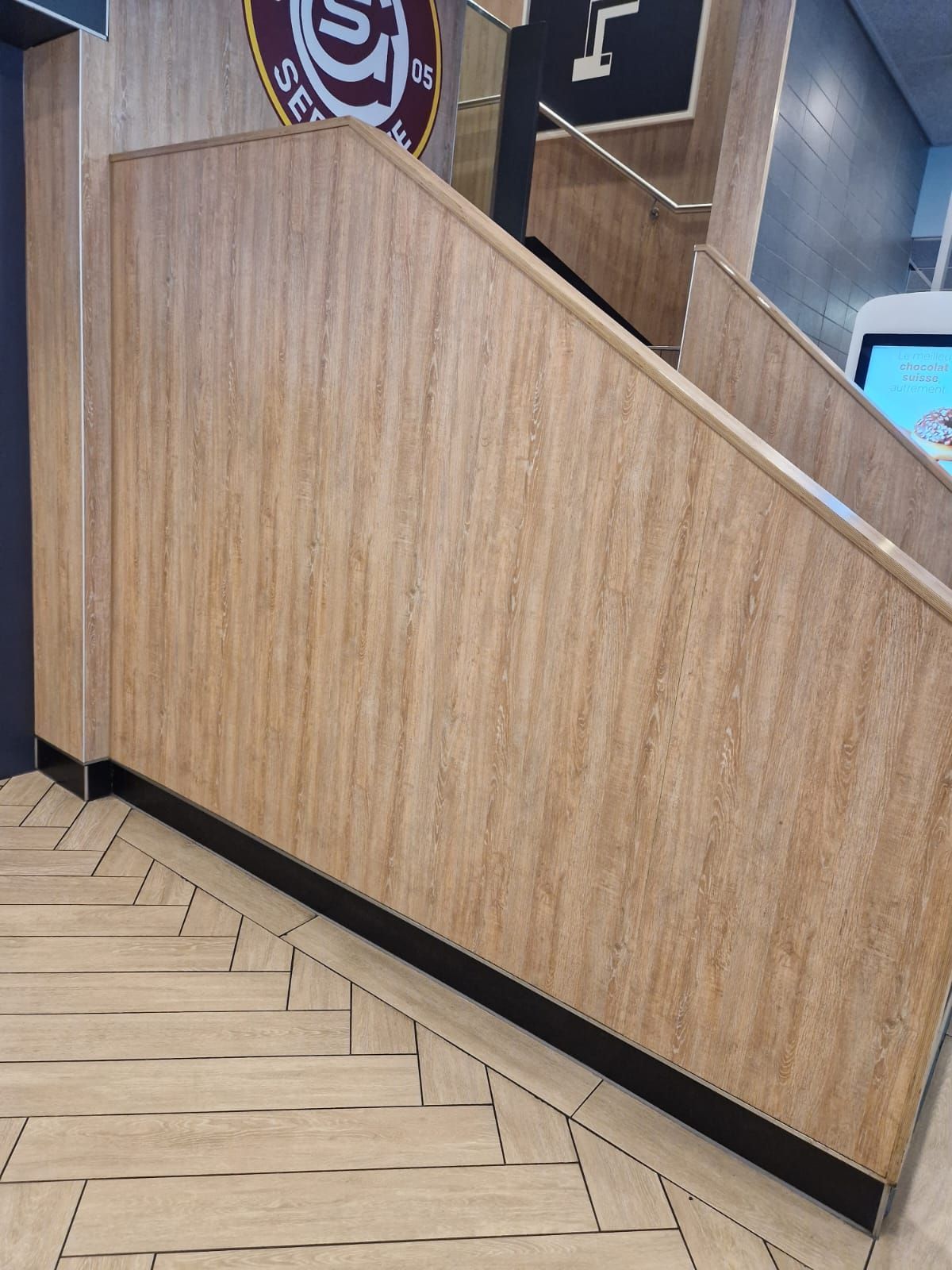 Revestimiento de madera junto a escaleras con suelo en forma de espiga, molduras negras, interior del edificio.
