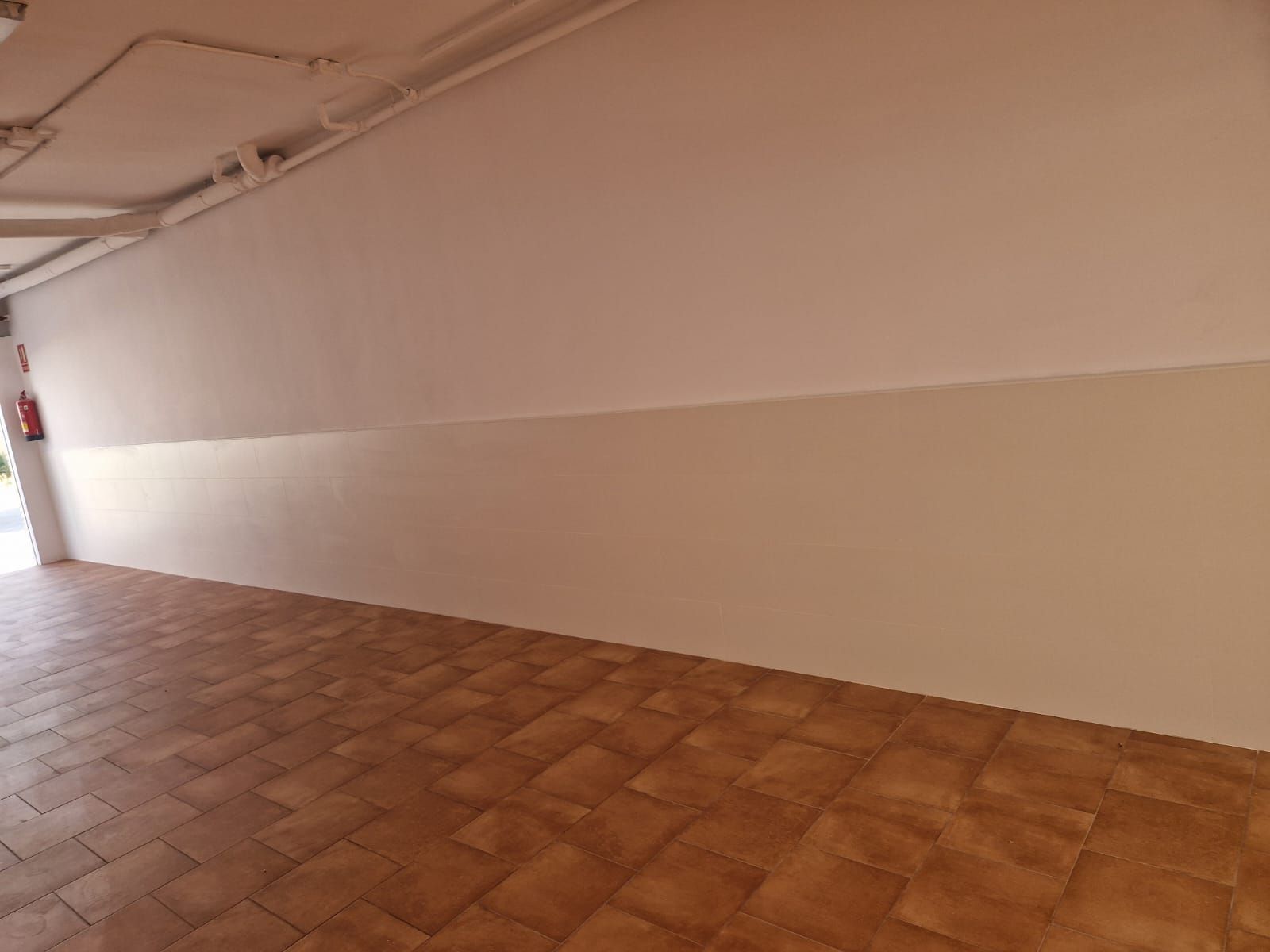 Habitación vacía con suelo de baldosas y paredes de color beige.