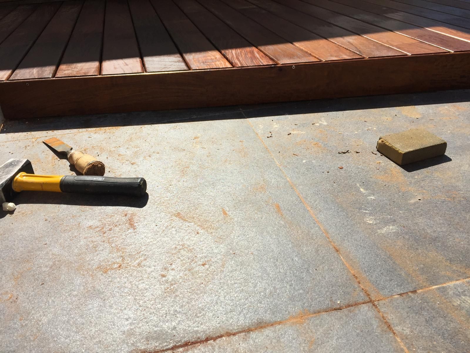 Hay un martillo en el suelo junto a un ladrillo.