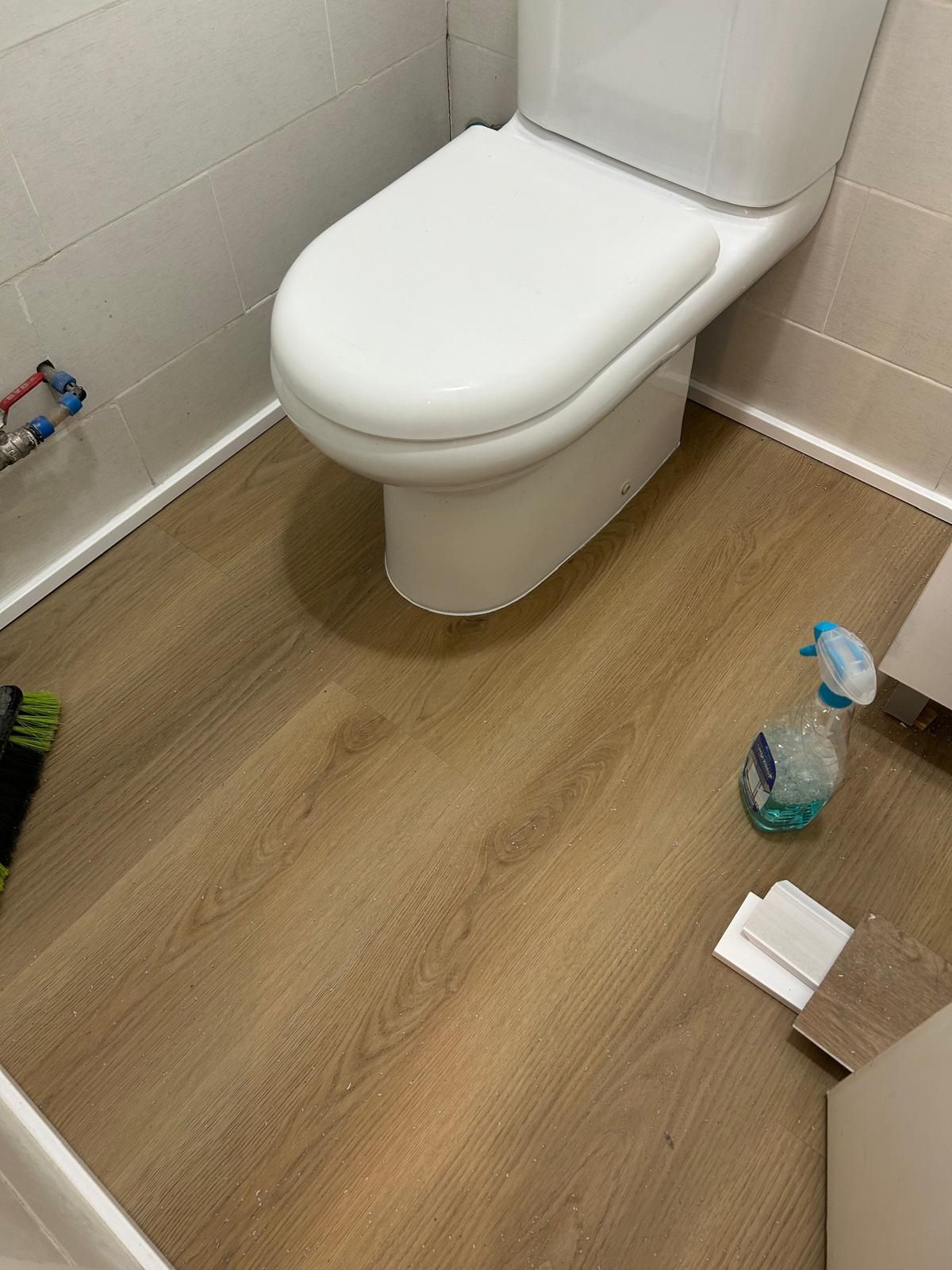 Un inodoro está sentado sobre un piso de madera en un baño.