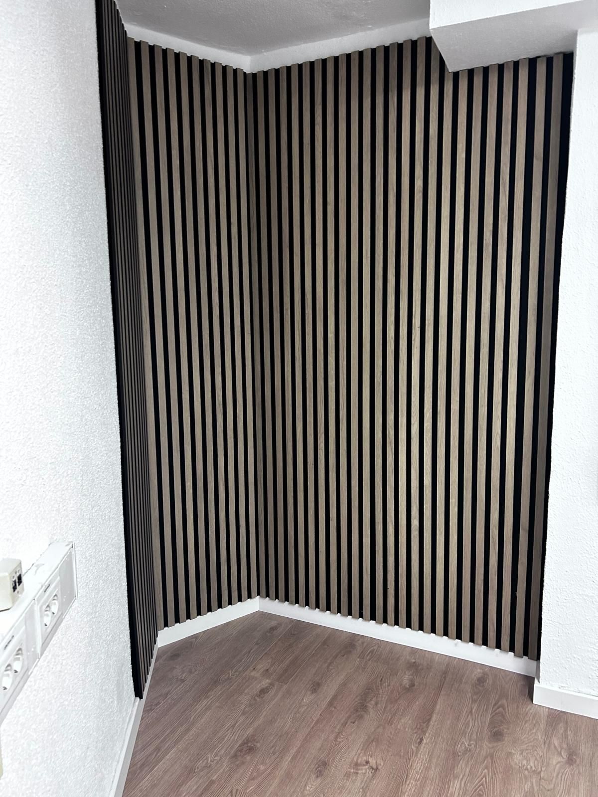 Un rincón de una habitación con papel pintado a rayas y suelos de madera.