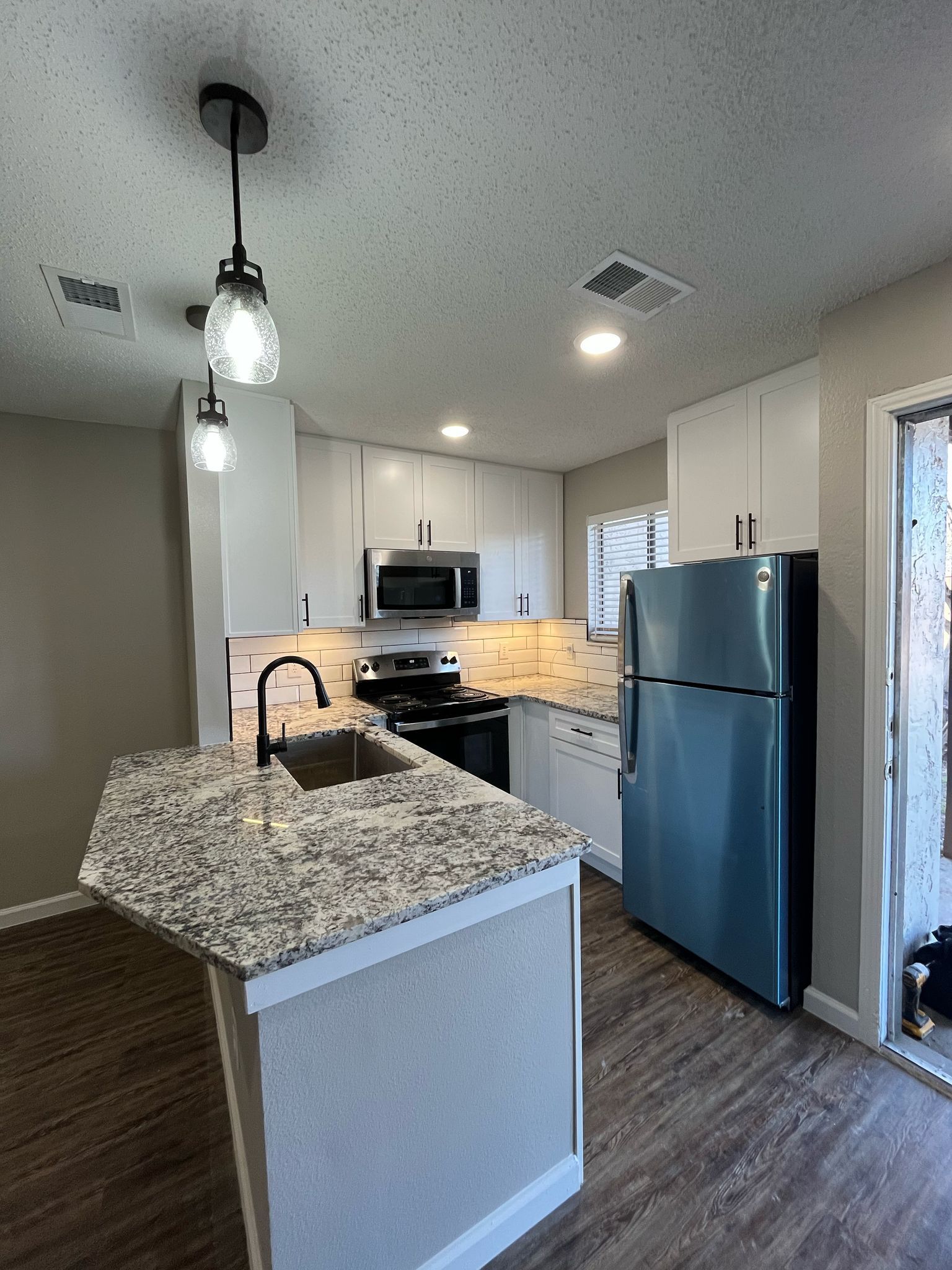 Una cocina con refrigerador de acero inoxidable y encimera de granito.