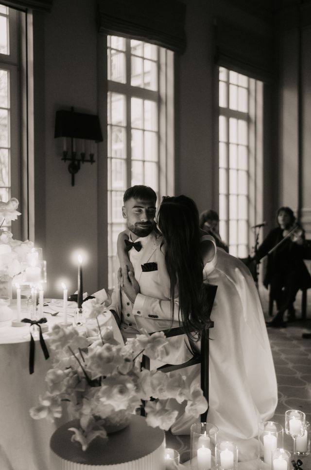 Die Braut küsst den Bräutigam beim Hochzeitsempfang, umgeben von Kerzen und Blumen.