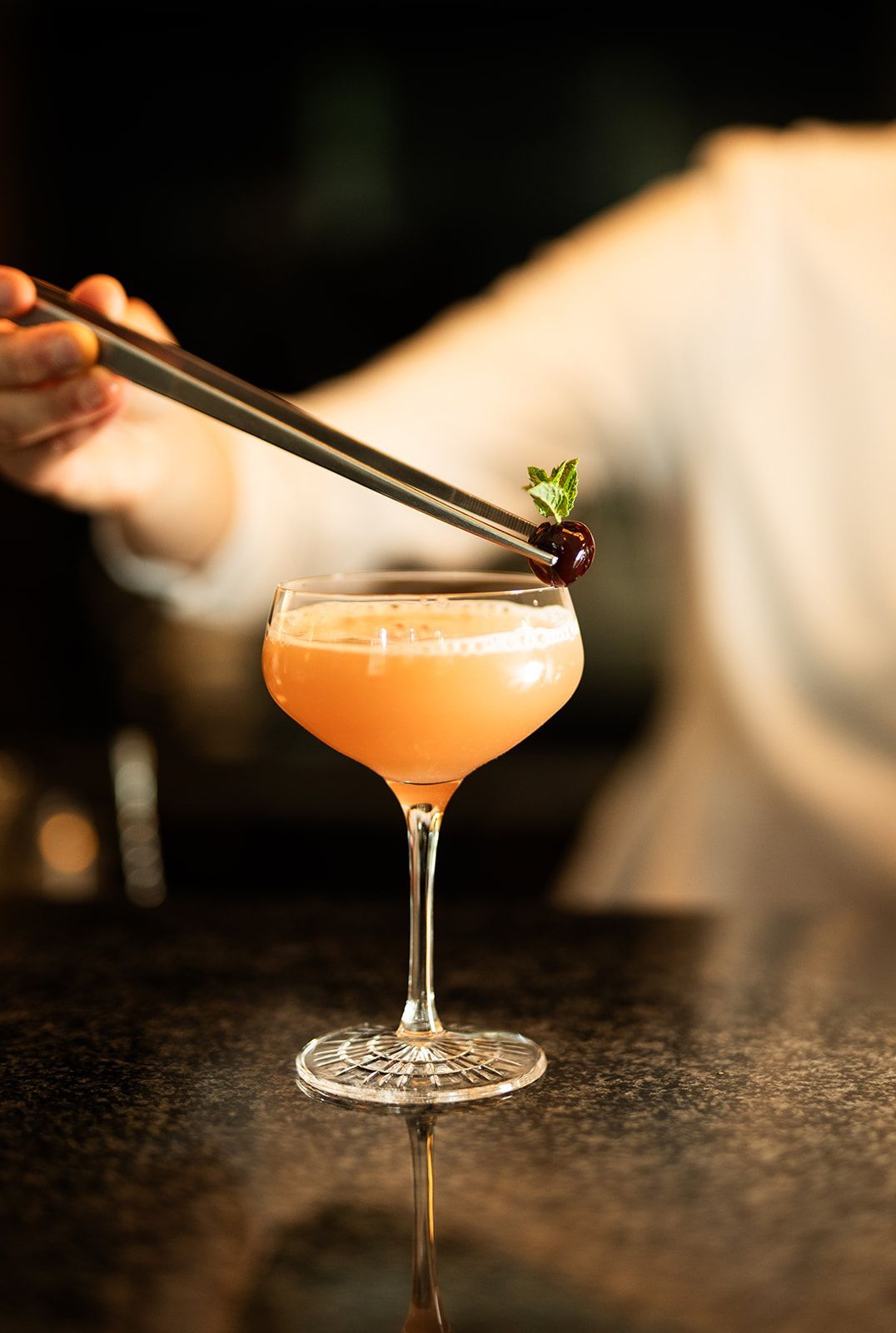 Cocktail in einem geriffelten Glas mit Eis und einer Zitronenzeste auf einer Holzoberfläche.