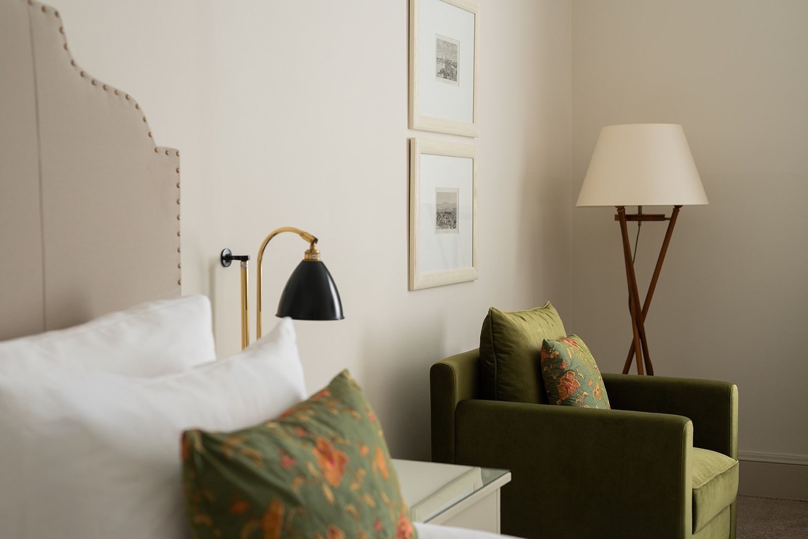 Schlafzimmerinterieur mit Bett, grünem Sessel und Stehlampe.