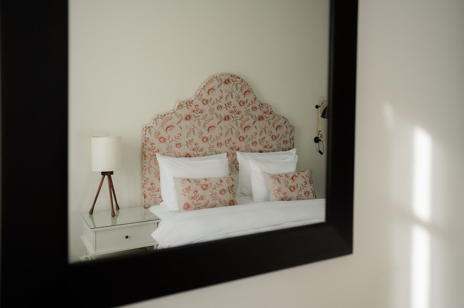 The reflection shows a bed with a floral-patterned headboard and matching decorative pillows in a bedroom.