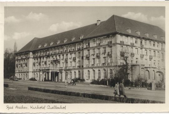Hoteleingang mit großen Säulen und dem Schriftzug „Quellenhof“ über der Tür.