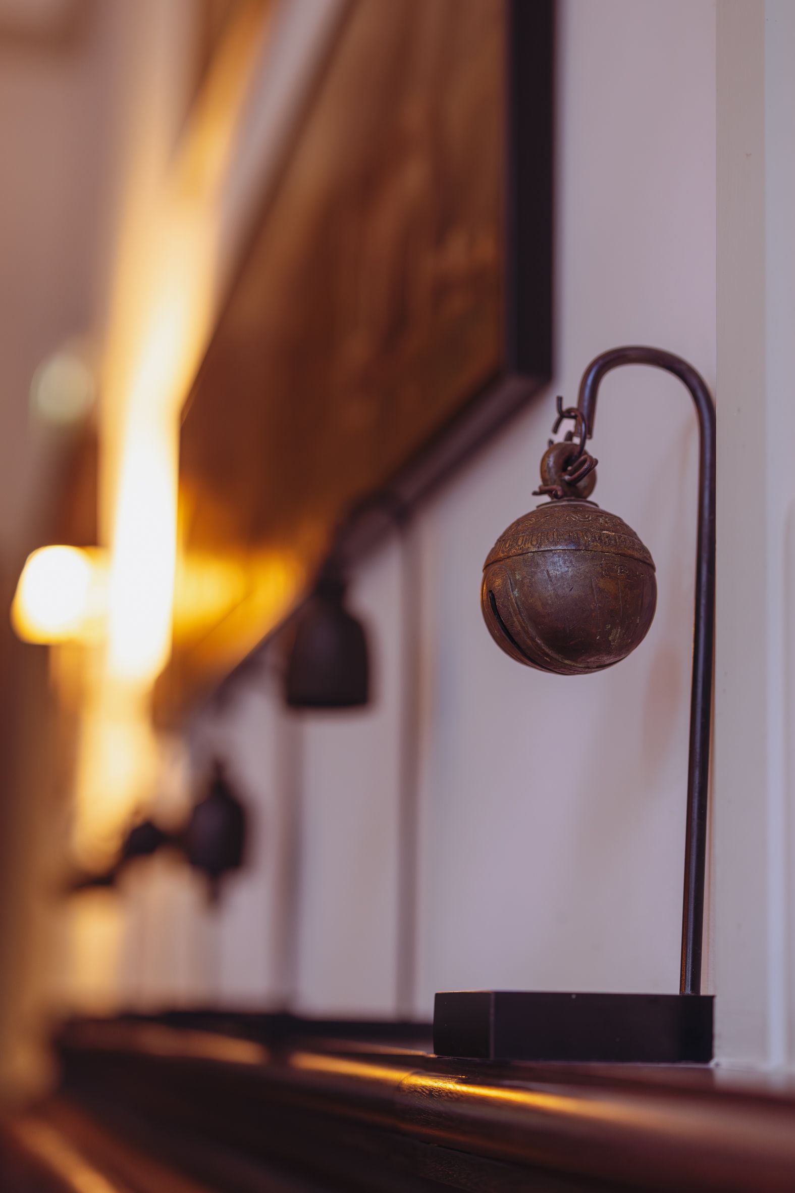 A metal ornament hangs from a decorative holder on a wooden mantelpiece.
