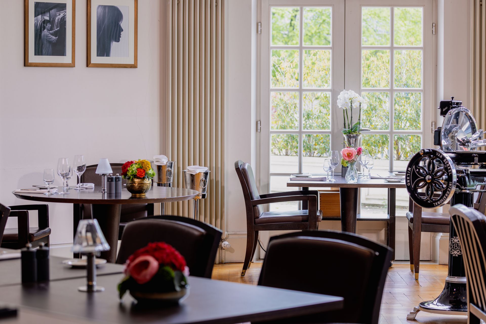 Restaurantinterieur mit gedeckten Tischen, Fenstern und Kunstwerken.