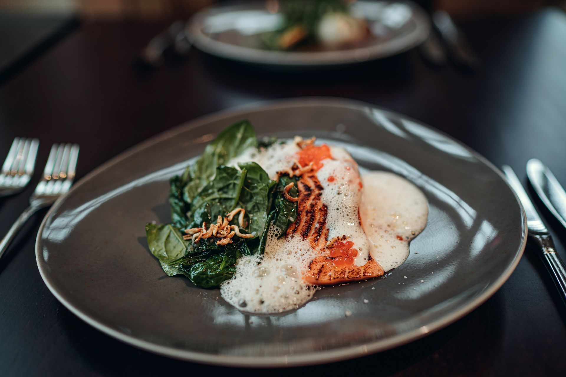 Restaurantinterieur mit gedeckten Tischen, Fenstern und Kunstwerken.