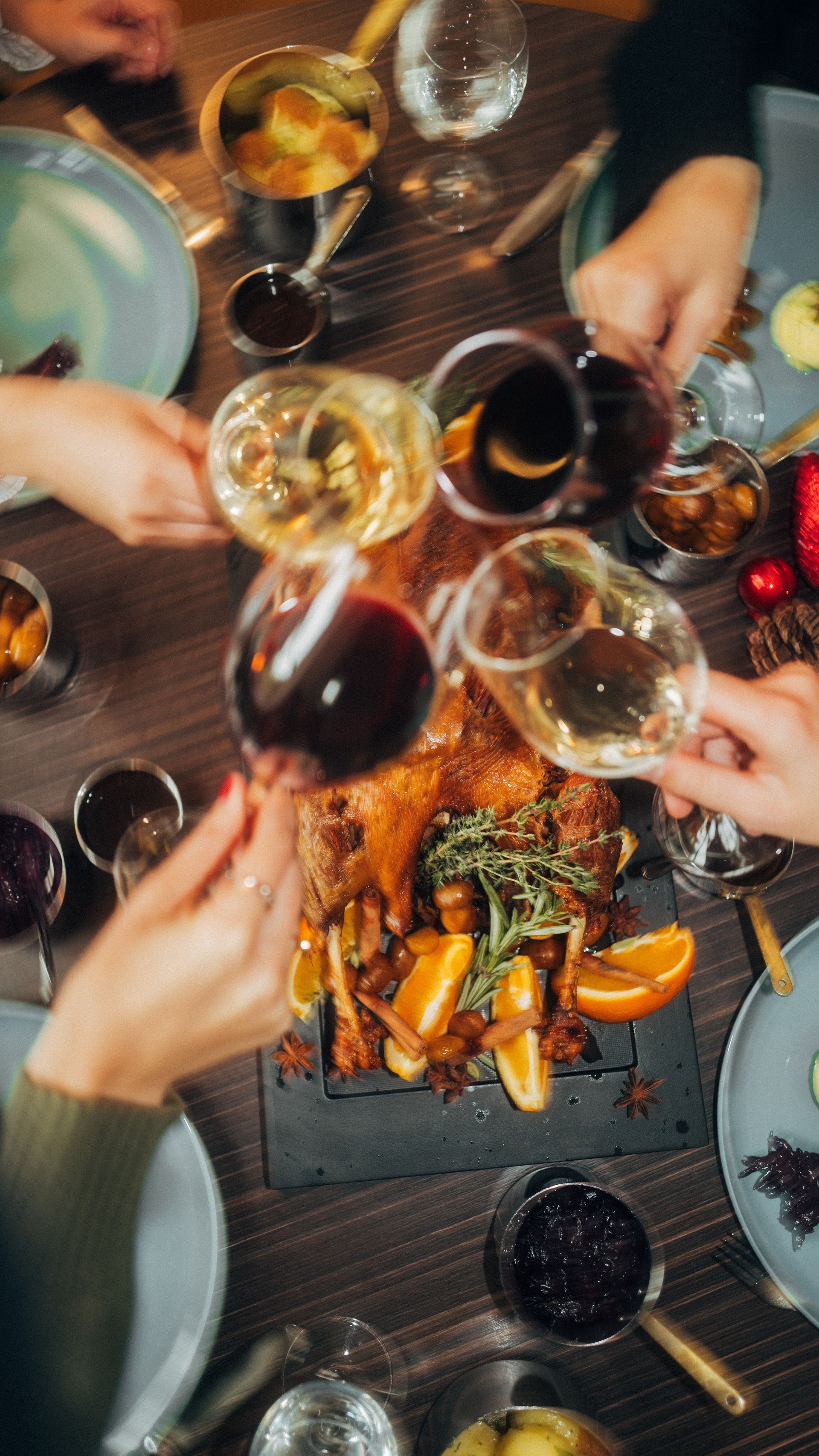 Menschen speisen an einem Tisch und genießen Essen und Wein. Elegantes Ambiente, Blumen, Kerzenlicht.