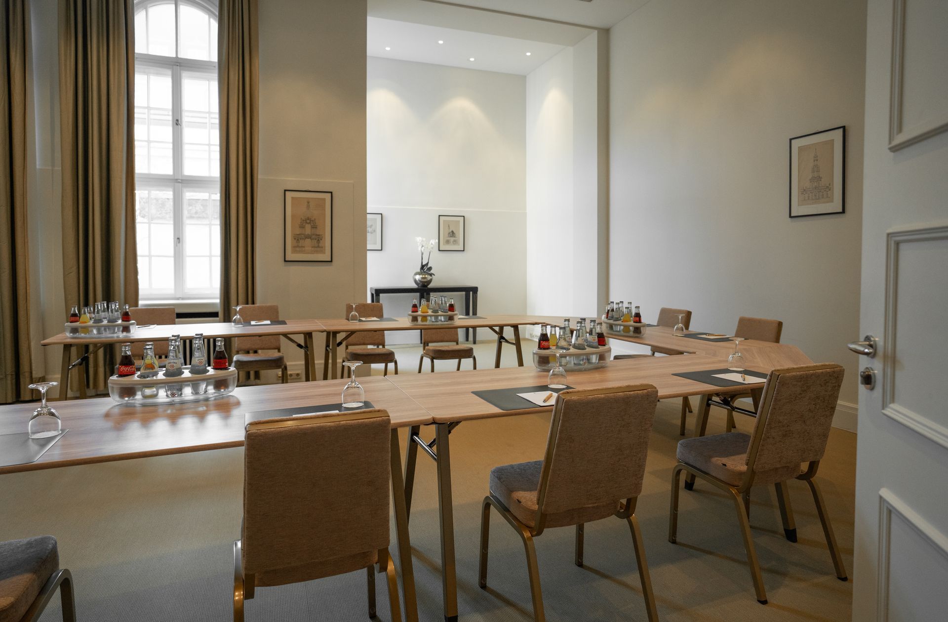 Ein für ein Meeting eingerichteter Konferenzraum mit einem U-förmigen Tisch, Stühlen und großen Fenstern.