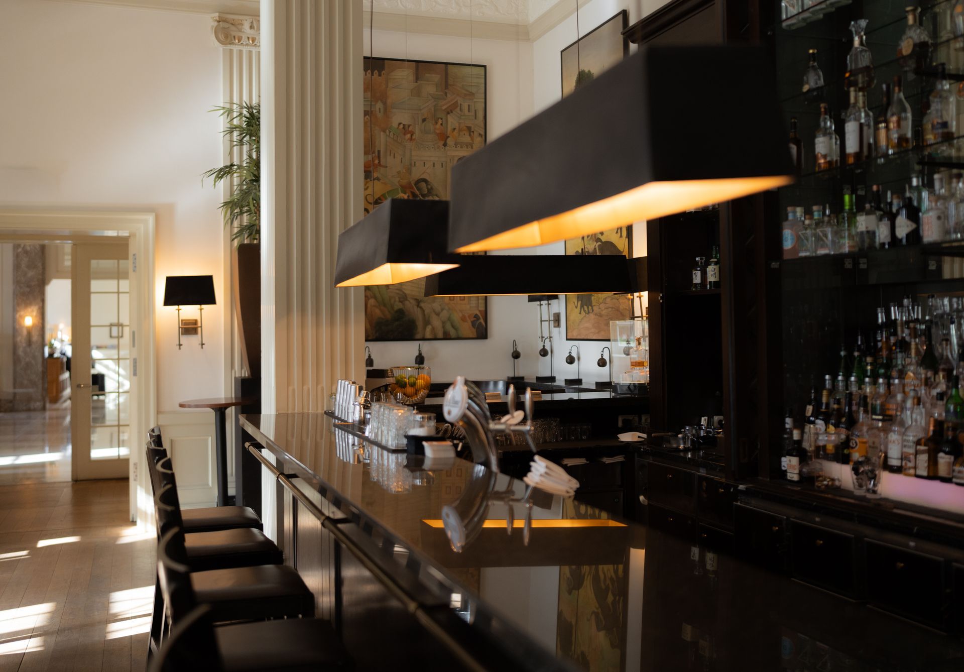 Interieur mit Ledersesseln, rundem Tisch, hohen Fenstern mit Jalousien und gerahmten Tierbildern.