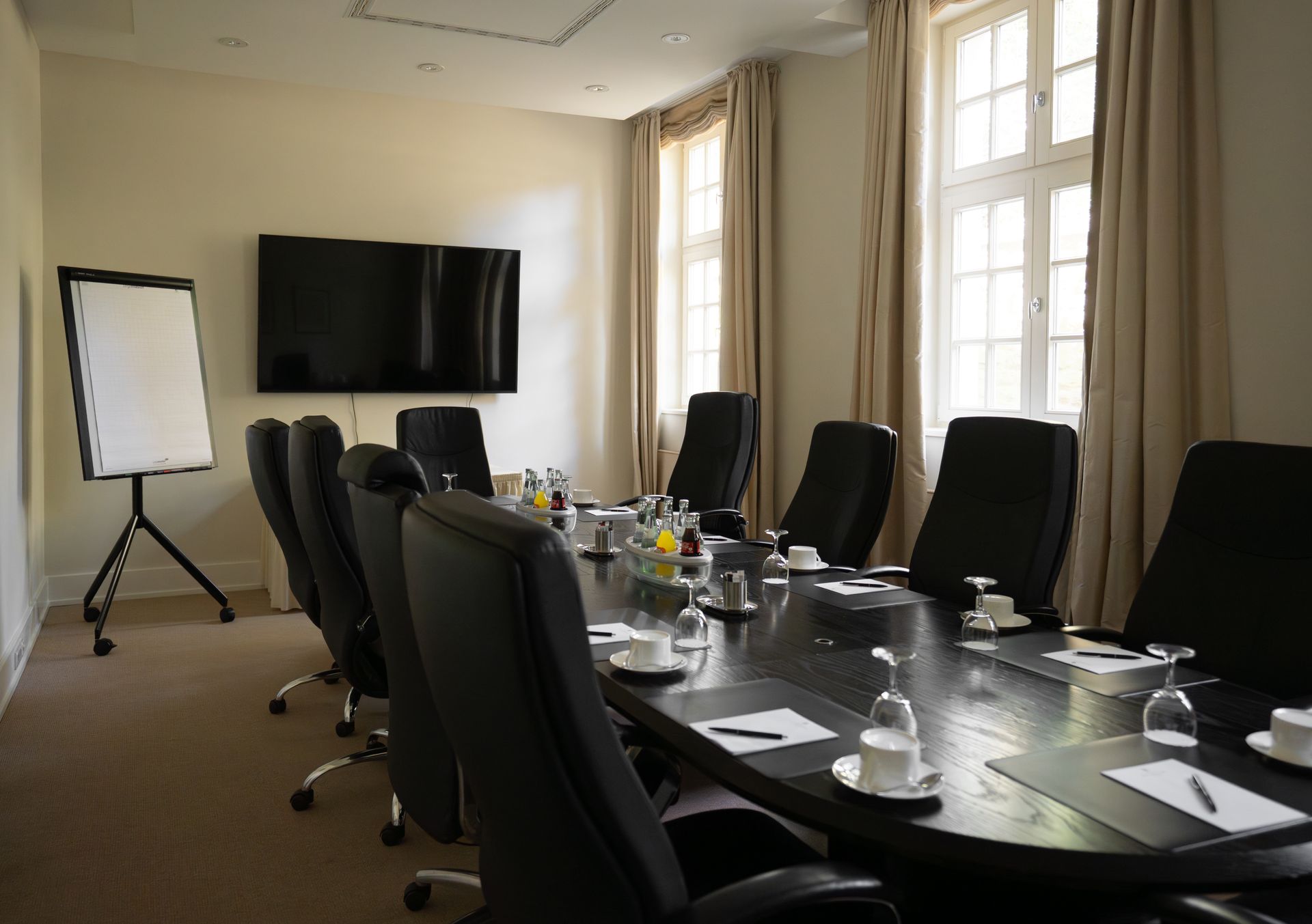 Ein Konferenztisch mit Getränken und Notizblöcken in einem neutral gehaltenen Raum.