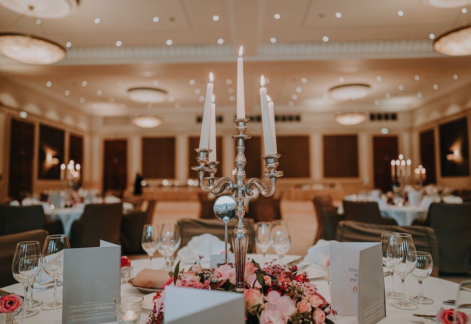 Elegante Tischdekoration für den Hochzeitsempfang mit Kandelaber, Blumengesteck und Platzkarten.