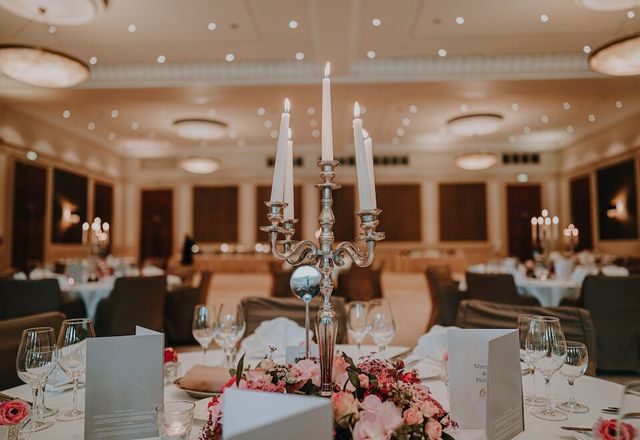 Elegante Tischdekoration für den Hochzeitsempfang mit Kandelaber, Blumengesteck und Platzkarten.