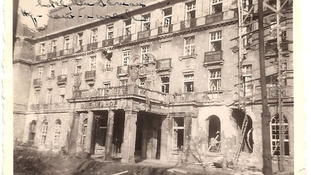 Verfallenes mehrstöckiges Gebäude mit Säulen und Balkonen. Rechts ist ein Gerüst zu sehen.