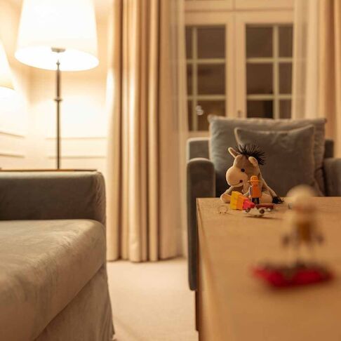 Gemütliches Wohnzimmer mit Lampe, Sofa, Sessel und hölzernem Couchtisch mit Spielzeug.