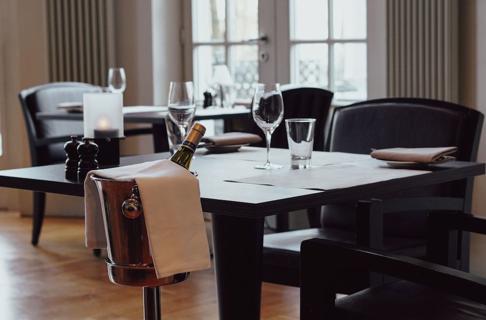 Frau am Fenster, durch das Sonnenlicht strömt, sie schaut hinaus. Weißes Kleid, Tulpen in der Vase.