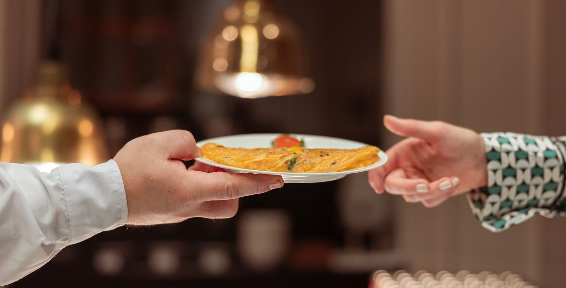 Frau schaut aus dem Fenster in die helle Sonne, Blumen auf dem Fensterbrett.