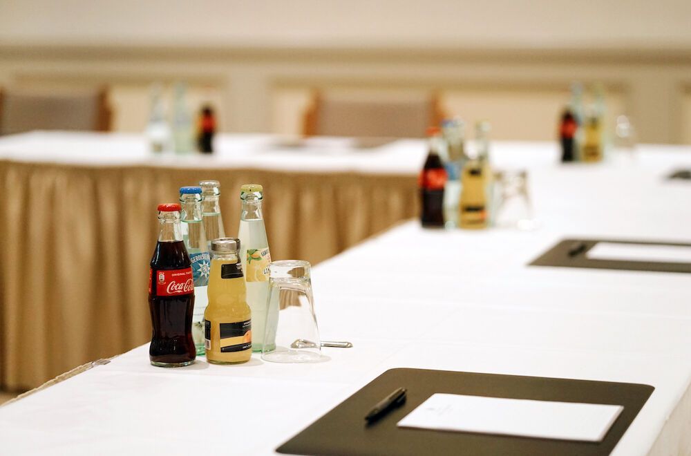 Ein Konferenztisch mit Getränken und Notizblöcken in einem neutral gehaltenen Raum.