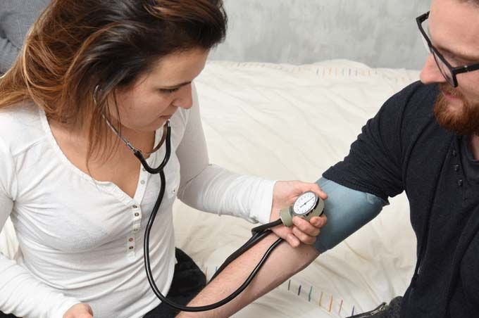 Une femme prend la tension artérielle d'un homme à l'aide d'un stéthoscope et d'un brassard placé sur son bras.