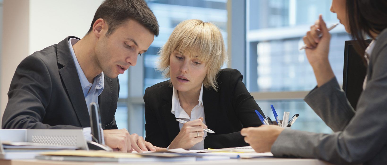 Trois hommes d'affaires examinent des documents dans un bureau.