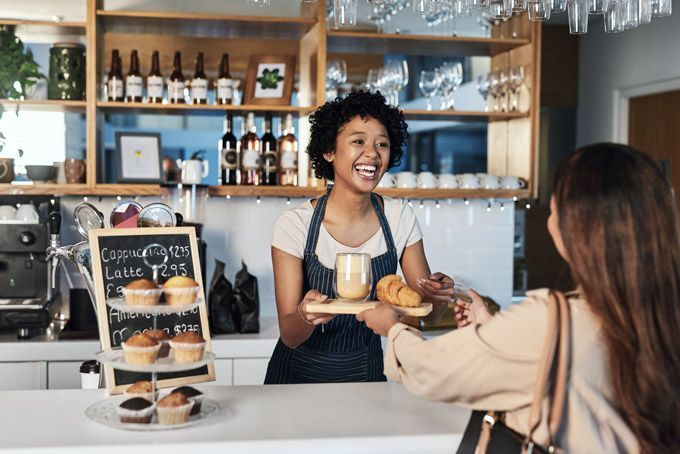 Un barista sert une boisson et une pâtisserie à un client au comptoir d'un café.