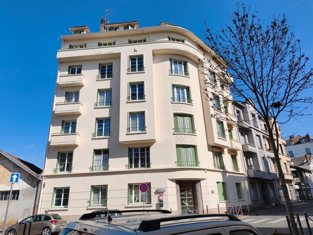 Un immeuble d'appartements de six étages aux couleurs claires et aux formes architecturales courbes, par une journée ensoleillée.