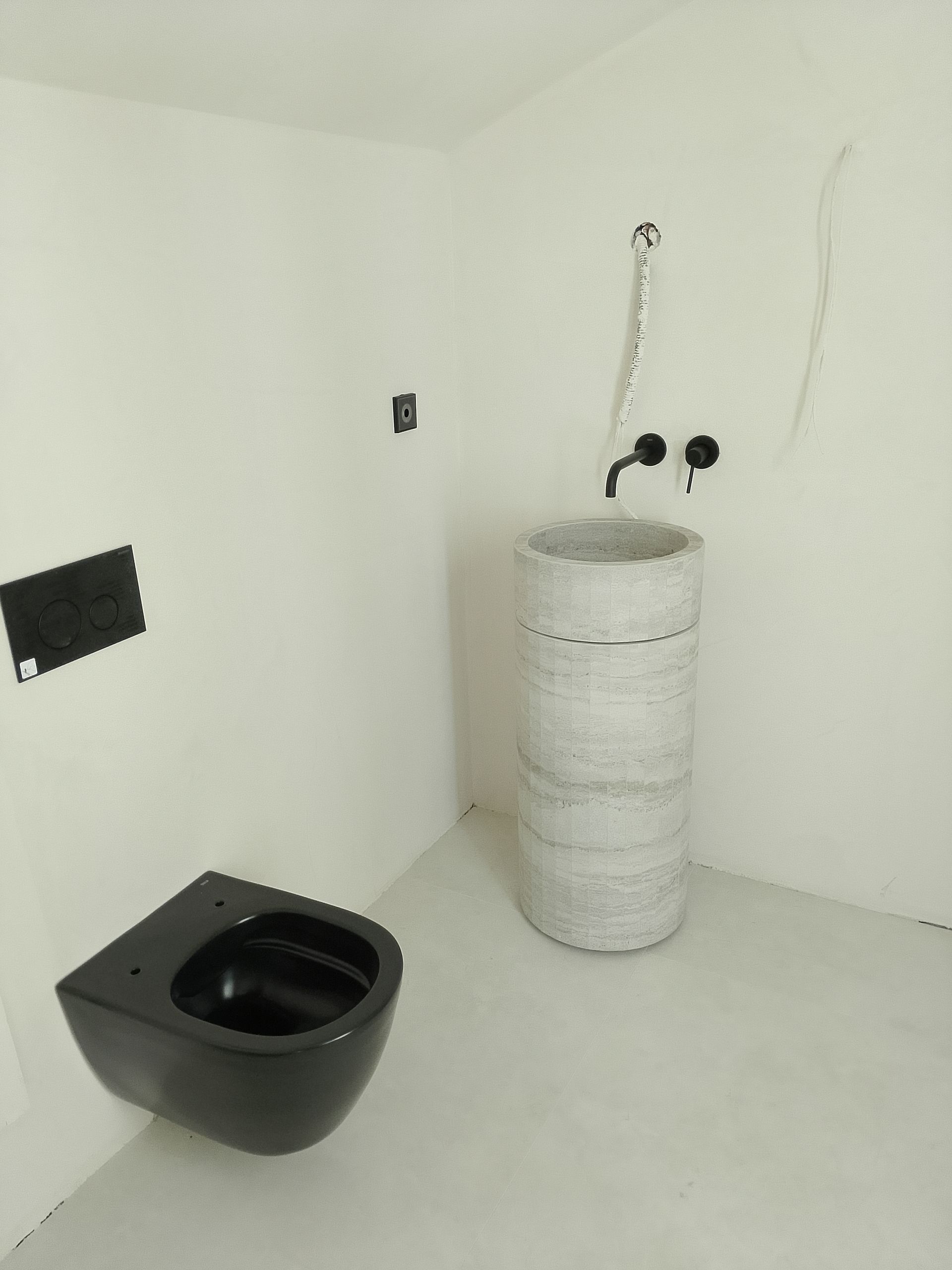 Baño moderno con inodoro y lavabo negros contra paredes blancas.