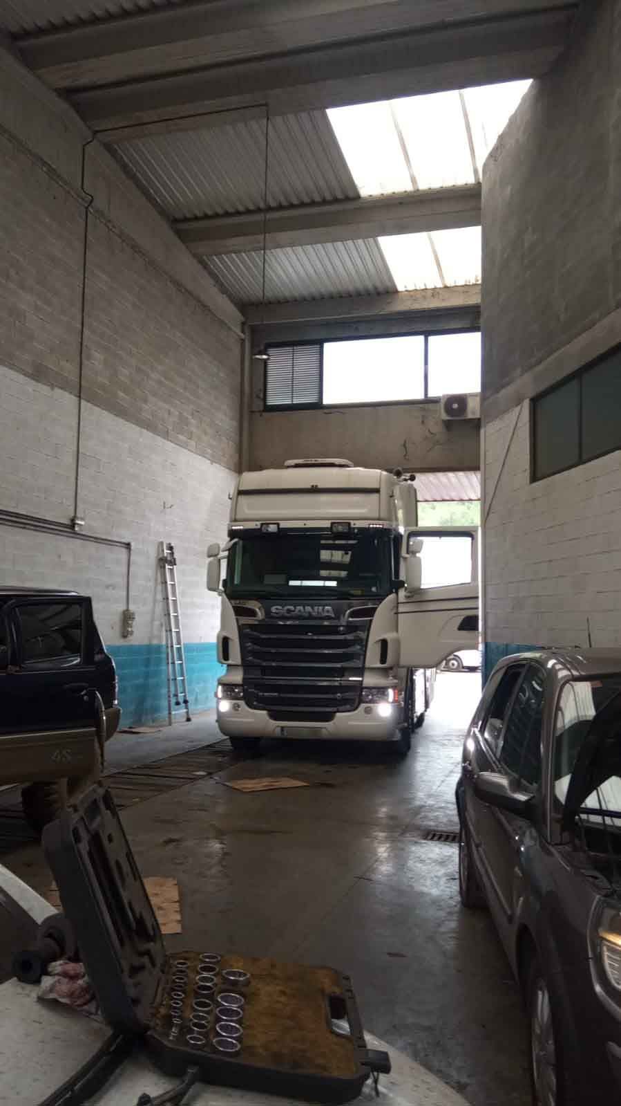 Un camión está estacionado en un garaje al lado de un coche.