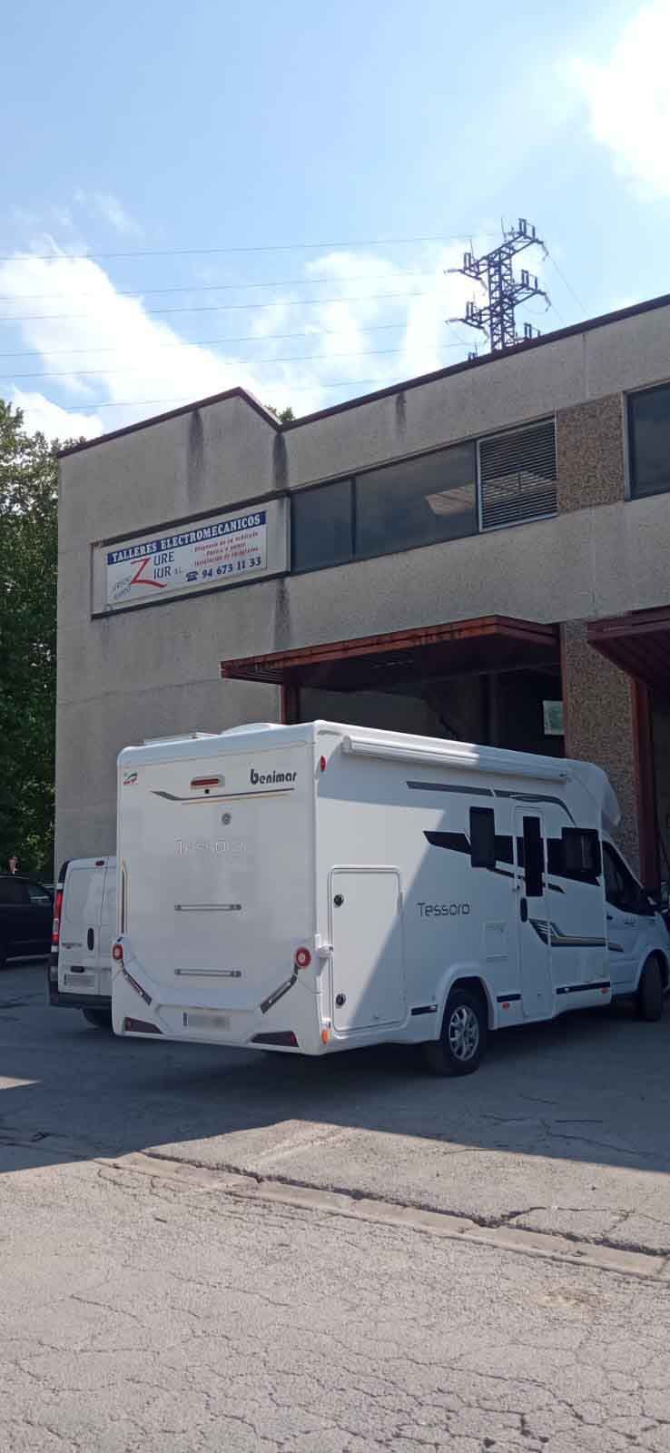 Una casa rodante blanca está estacionada frente a un edificio.