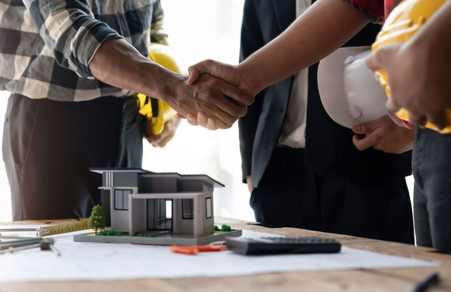 Deux personnes qui se serrent la main avec un modèle 3D d'une maison en-dessous