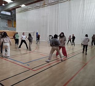 Un grupo de personas está jugando voleibol en un gimnasio.