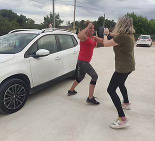 Dos mujeres están paradas una al lado de la otra frente a un automóvil blanco.