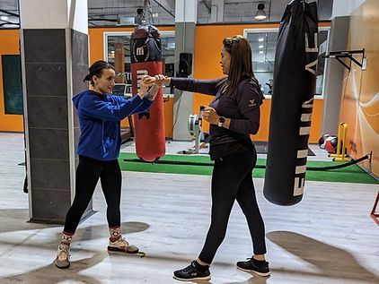 Dos mujeres están practicando artes marciales en un gimnasio.
